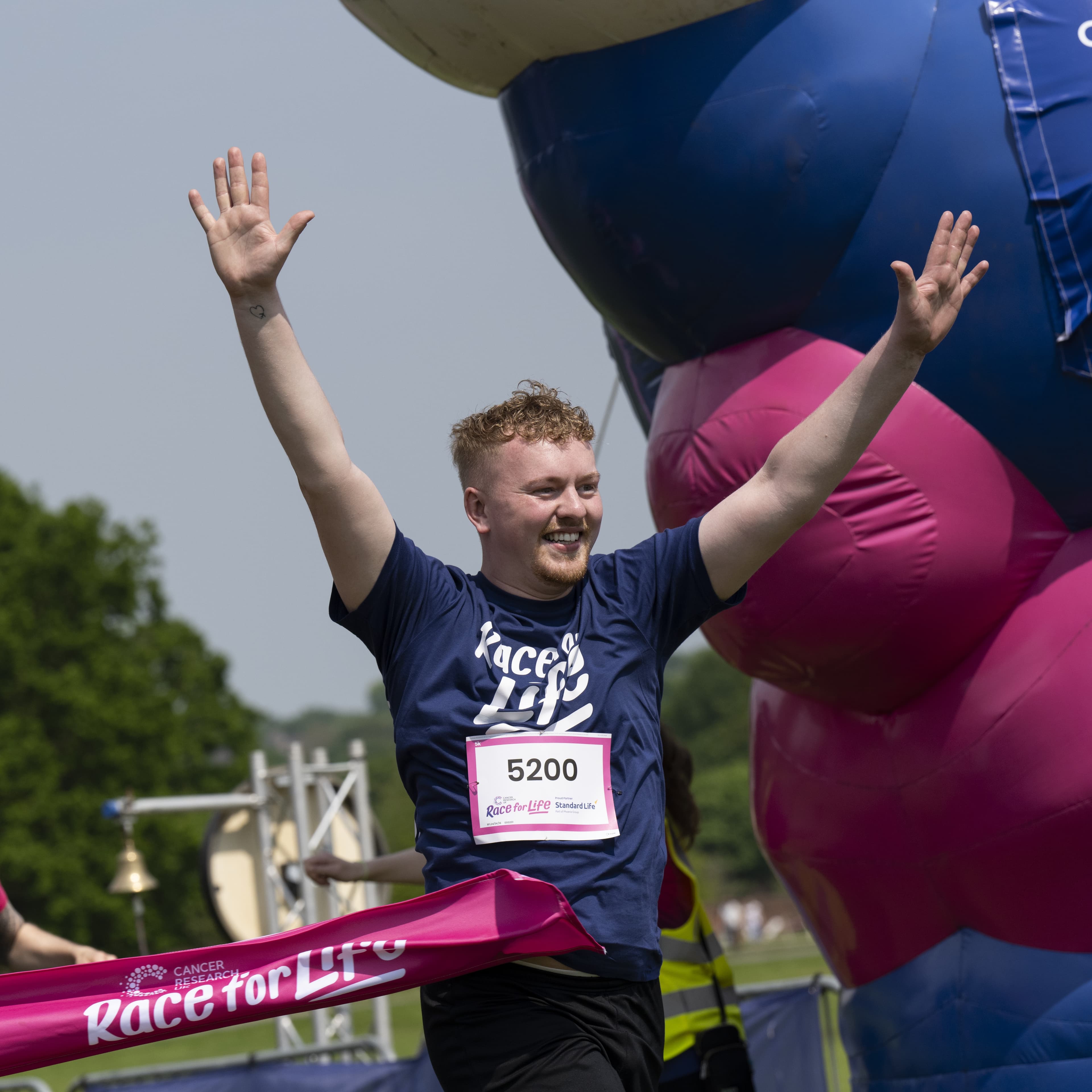 A young man crossing the finish line with his hands in the air jubilantly.